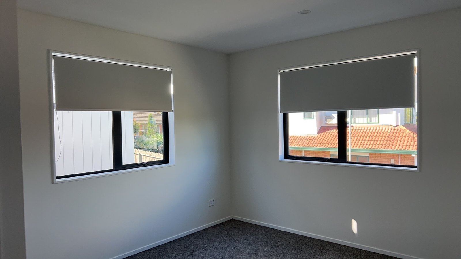 Roller blinds in a clean double-window bedroom
