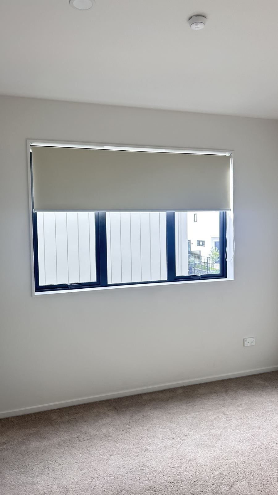 Beige blockout roller blind in a bedroom