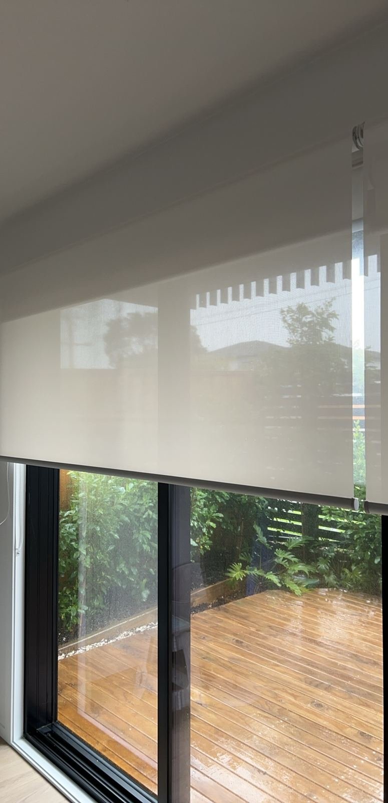 Sunscreen roller blind overlooking a wet deck garden